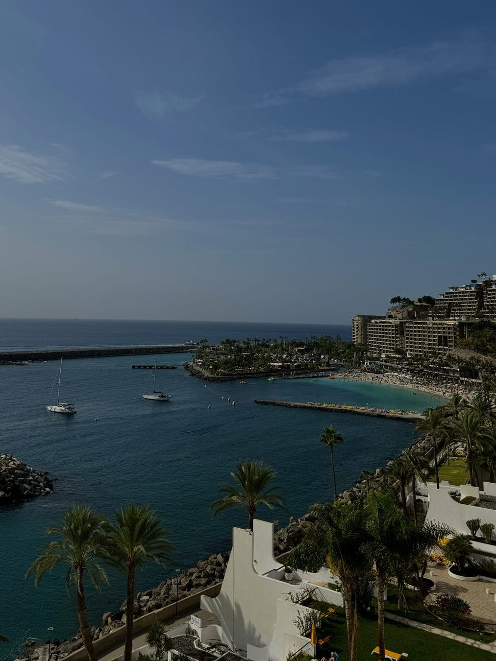 Blick vom Balkon über die Bucht von Anfi mit Segelbooten und Palmen