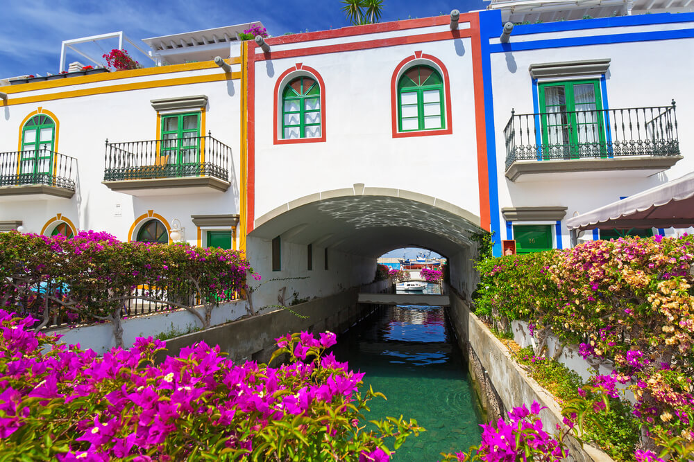 Bunt gerahmte Häuser mit Bougainvillea an einem Kanal in Puerto de Mogán