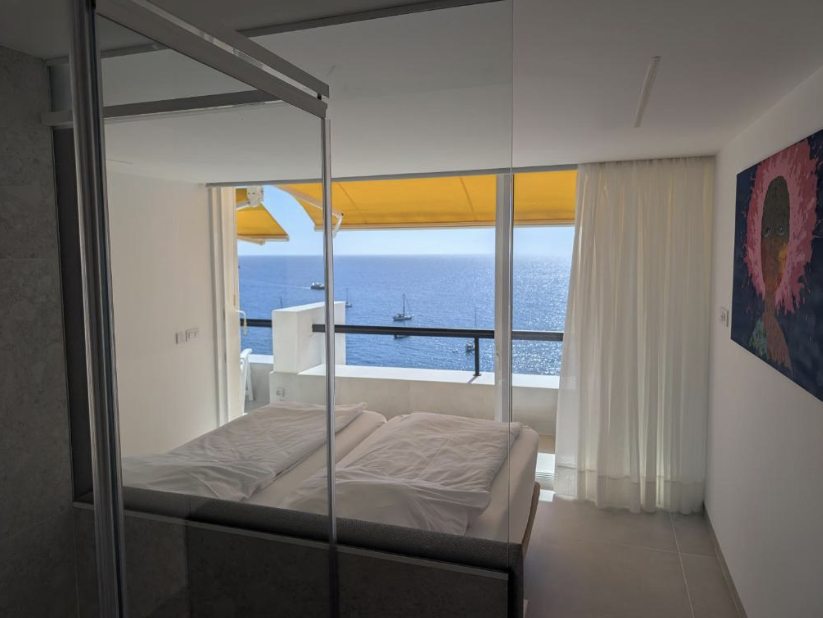 Schlafzimmer mit großem Fenster und direktem Blick auf das Meer vom Bett aus